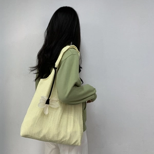 Detail of light yellow pleated canvas tote bag with a white flower charm accessory