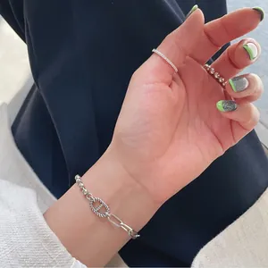 Detail of silver S925 beaded chain bracelet and minimalist rings worn by a model