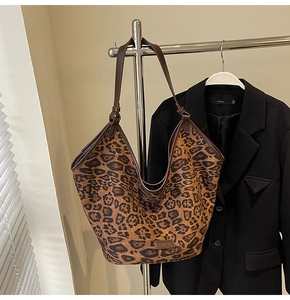 Detail of large leopard print tote bag hanging with a black blazer on a minimalist wall
