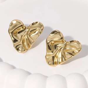 Detaillierte Nahaufnahme goldener Herzohrstecker mit einer einzigartigen Knittermetalltextur
