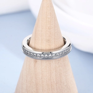 Detailed view of silver eternity ring with channel-set diamonds on a wooden stand