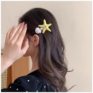 Detail of starfish and shell hair clip with pearls on long wavy brown hair