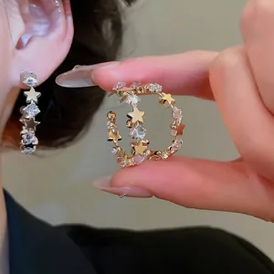 Sparkling zircon star geometric C-shaped gold hoop earrings worn by a female model