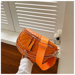 Detail of orange quilted crossbody bag featuring gold metal chains and wide fabric strap