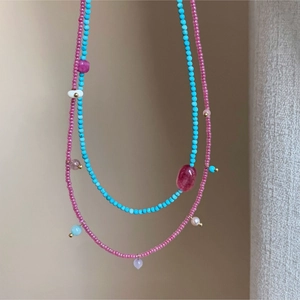 Detail of pink natural stone and turquoise beaded necklace with golden pendants