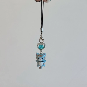 Close-up of blue striped cat keychain charm with a metal heart and black lanyard