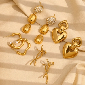 Chic 18K gold plated earring set with heart, pearl, and bow designs on beige fabric