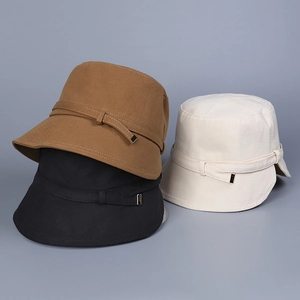 Detailed stack of cotton bucket hats in brown, black, and beige with metal buckles