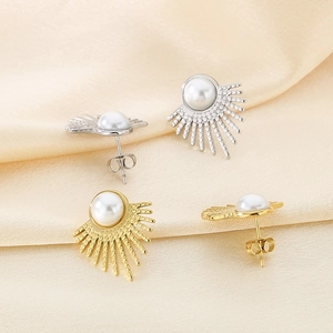 Elegant gold and silver sunburst pearl stud earrings on a silk background