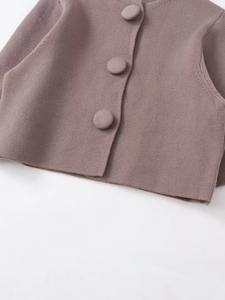 Détail du cardigan en maille à col rond avec boutons recouverts de tissu rose poudré