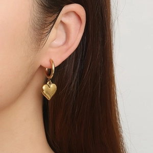 Fashionable 18K gold plated heart pendant hoop earrings worn by a model in close-up