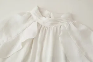 Detail of white glossy blouse with ruffled high neck and shoulder frill accents