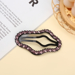 Detail of wavy black metal hair clip decorated with sparkling pink rhinestones