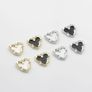 Eight mixed heart pendants in gold and silver with black enamel and wavy metal frames