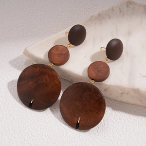 Détail de boucles d'oreilles vintage en bois superposé marron sur fond de marbre blanc