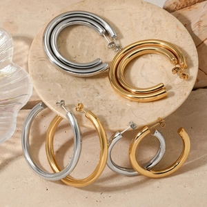 Polished gold and silver stainless steel chunky C-shaped hoop earrings on marble plate