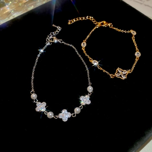 Detailed macro shot of vintage floral zircon and pearl bracelets on black velvet background