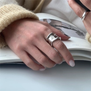 Close-up of irregular wide 925 silver ring worn on model's hand over a magazine