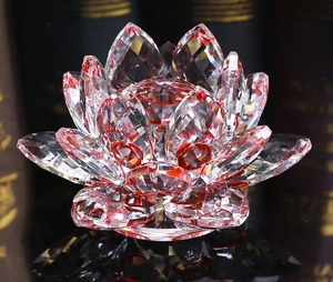Macro shot of red faceted crystal lotus ornament reflecting on a black glossy surface