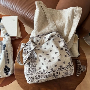 Détail de sacs en lin avec imprimé paisley et broderie ethnique sur une table en bois