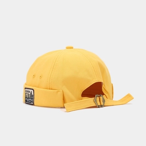 Close-up of mustard yellow canvas miki hat featuring vintage patch and metal buckle