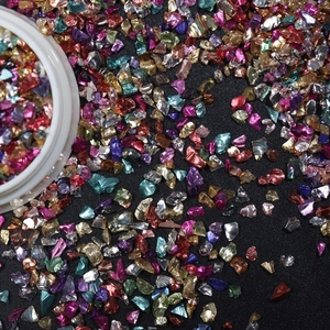 Macro shot of colorful irregular nail art glitter shards with metallic luster on black