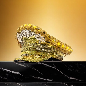 Macro shot of gold sequins and yellow gemstones on the brim of a luxury party captain hat