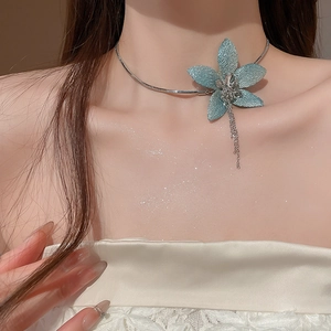 Close-up of blue glitter fabric flower choker with tassel details on a model neck