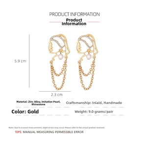 Detail view of gold alloy face earrings with tassel chains and pearl accents