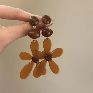 Detail shot of brown resin flower earrings with gold-tone hardware and marble texture