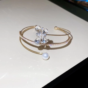 Macro detail of gold flower pearl cuff with sparkling zircon butterfly and fine crystals