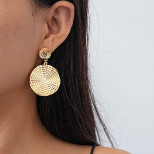 Detail of gold geometric round textured earring on a model showing metallic weave pattern