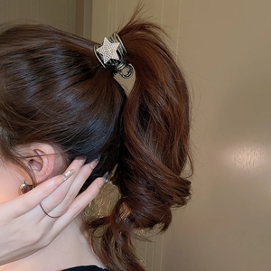 Close-up of a silver star-shaped hair claw clip with diamonds on high ponytail