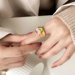 Golden wide band ring with pink enamel cherry pattern on hand for spring jewelry