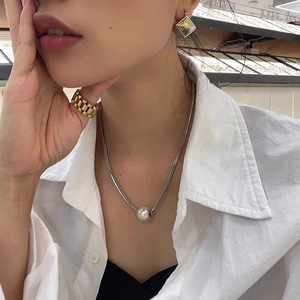 Detail of silver snake chain with pearl pendant and square earrings worn by model