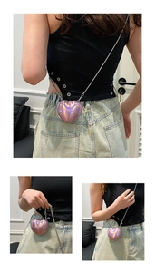 Close-up of heart-shaped laser acrylic mini bag with metal chain on person