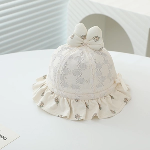 Détail du chapeau bébé avec dentelle ajourée, nœud floral et bord à volants