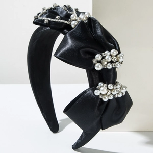 Détail du serre-tête en satin noir avec nœud multicouche, perles et strass brillants