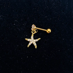 Detail view of a gold starfish earring with pavé zircon charms on black velvet