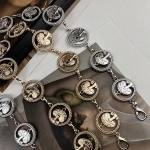 Macro shot of gold and silver metal waist chains featuring round mushroom pendants
