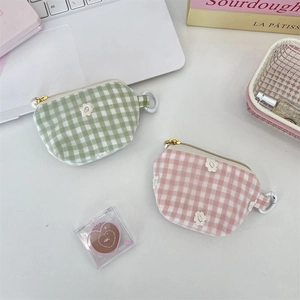 Close-up of checkered mini pouch with daisy embroidery and a gold zipper closure
