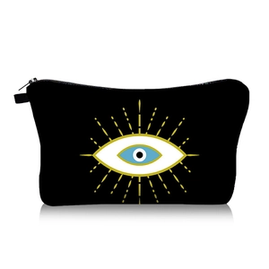 Close-up of a black canvas makeup bag featuring a blue and gold Evil Eye print and zipper