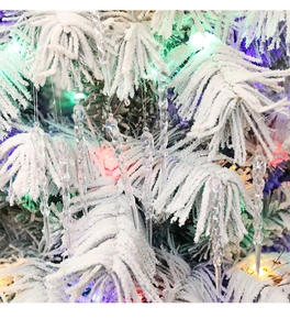 Close-up of clear spiral icicle ornaments hanging on a snowy Christmas tree branch