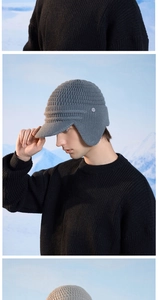 Detail of grey knitted winter hat featuring ear flaps and a brim for wind protection