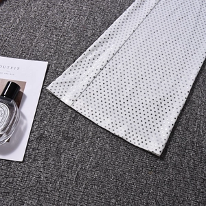 Gros plan du tissu blanc avec paillettes argentées sur un fond gris texturé élégant