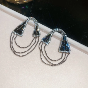 Détail de boucles d'oreilles à franges argentées avec pierres noires géométriques