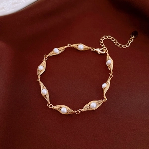 Detail shot of gold-plated wire-wrapped bracelet with eight white freshwater pearls
