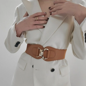 Detail of wide brown PU leather waist belt with gold geometric metal buckle on a white blazer