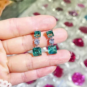 Détail de boucles d'oreilles en zircone émeraude carrée et plaqué argent à 3 pierres