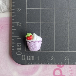 Miniature resin strawberry cupcake charm on a measuring mat for DIY jewelry making